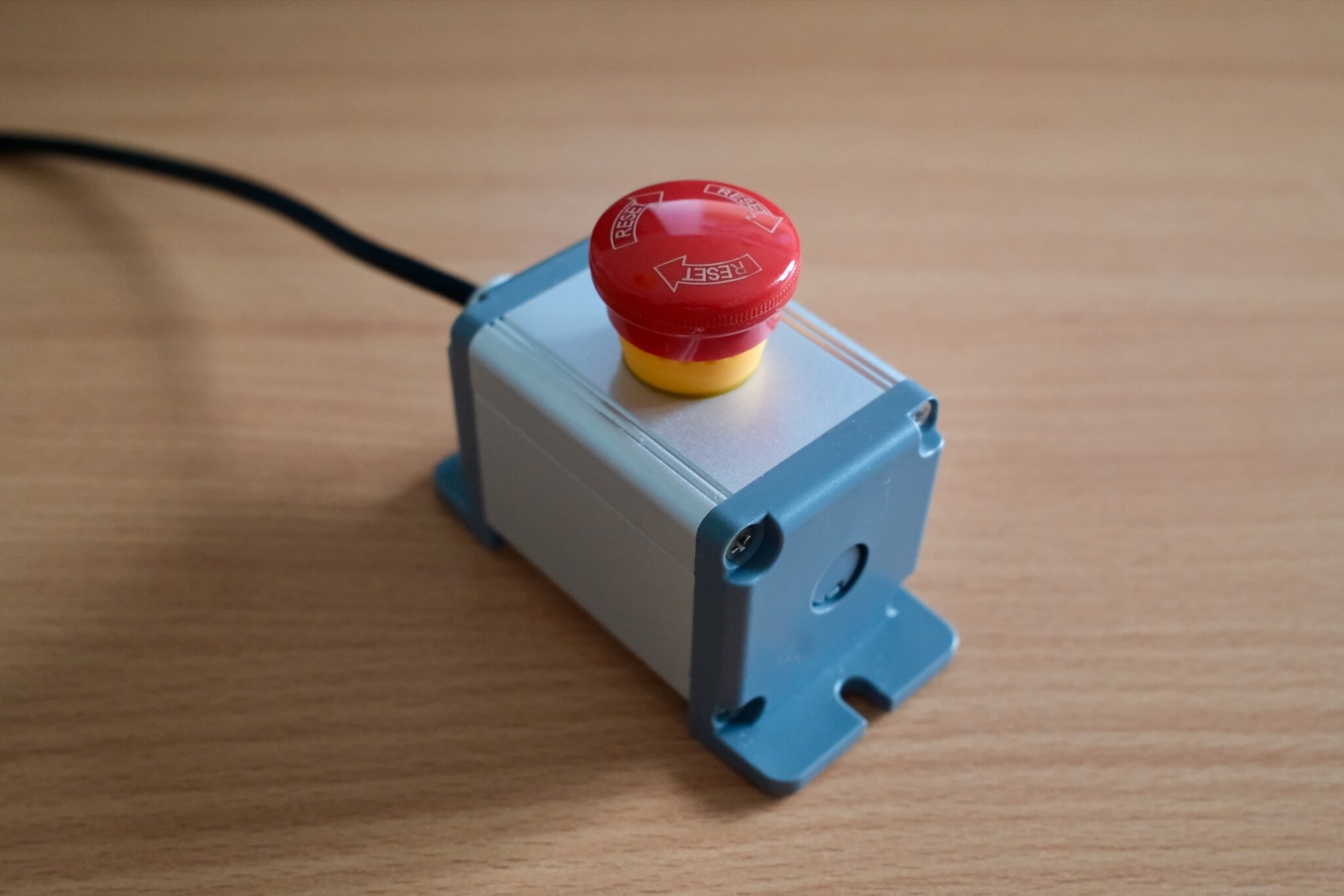 The red hardware emergency stop button on the desk.