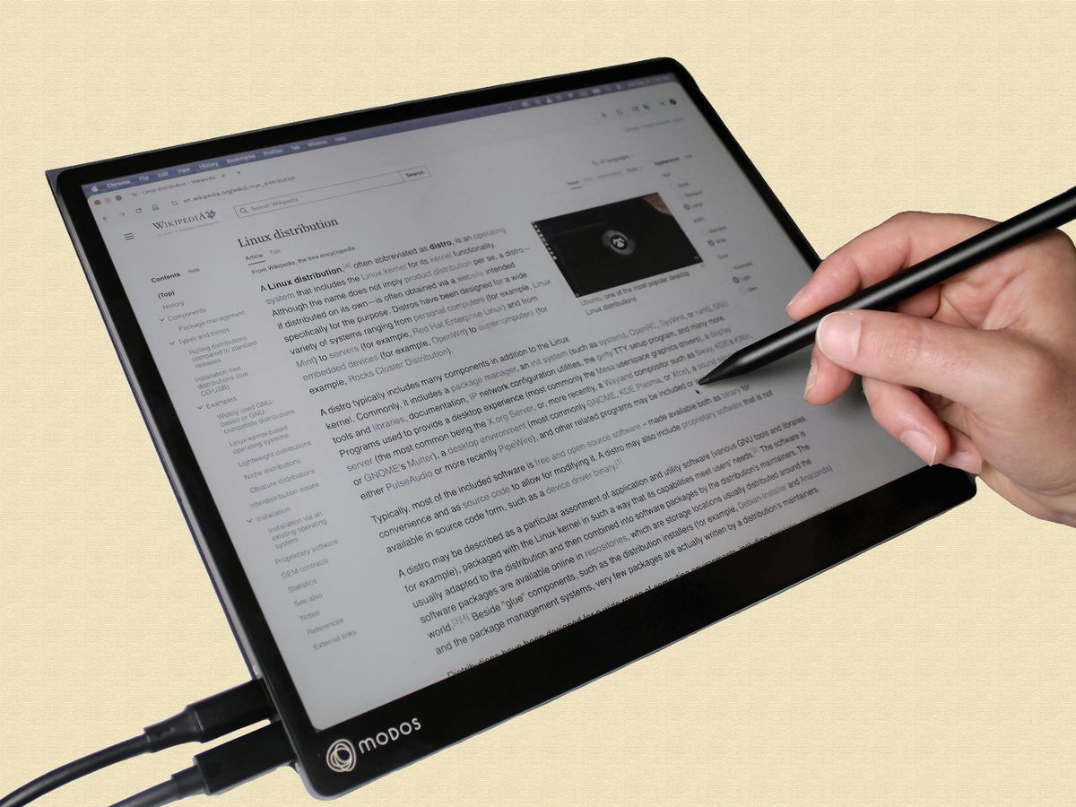 Close-up of a hand using a stylus on an e-paper PC monitor.
