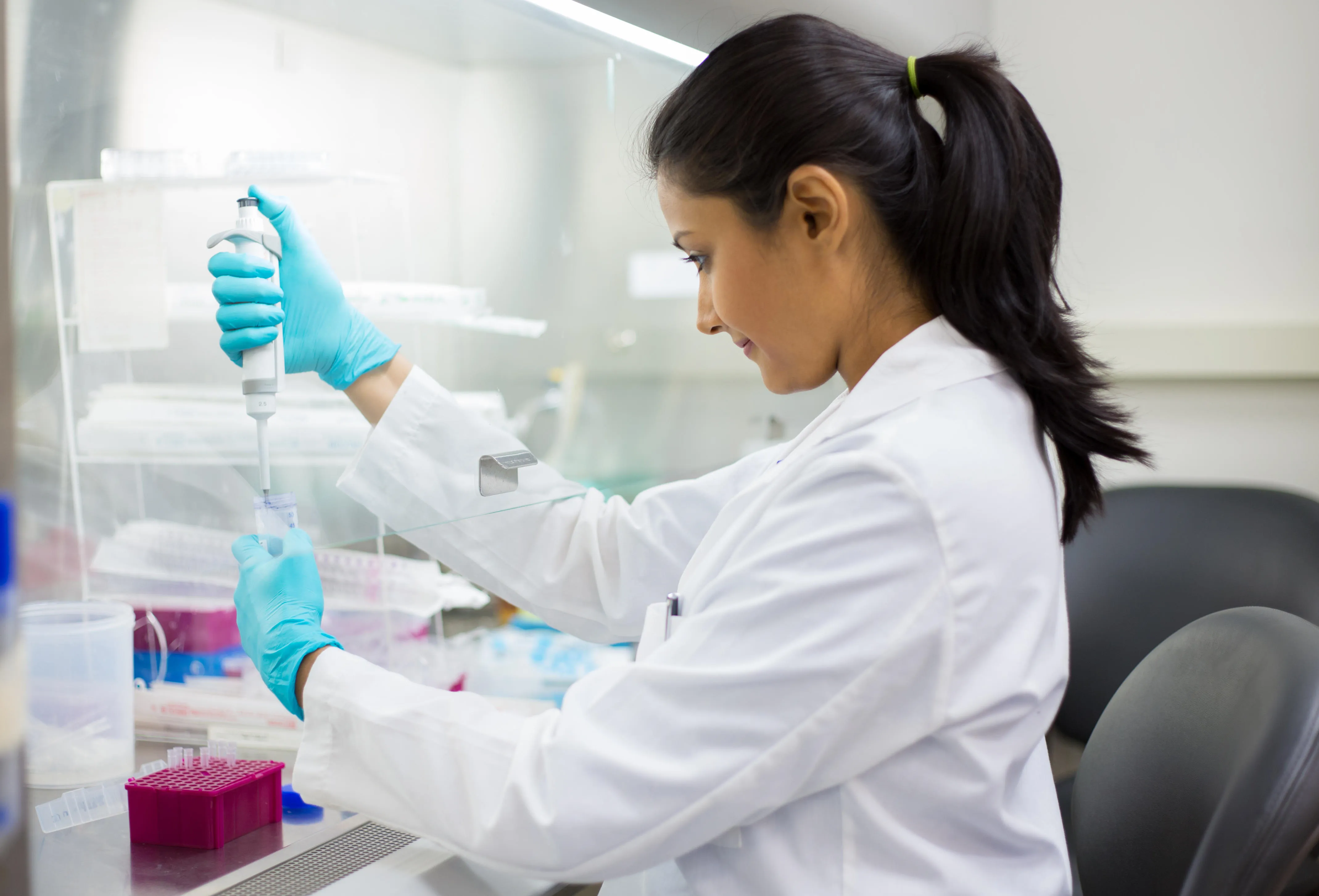 A female scientist placing liquid in a test tube.